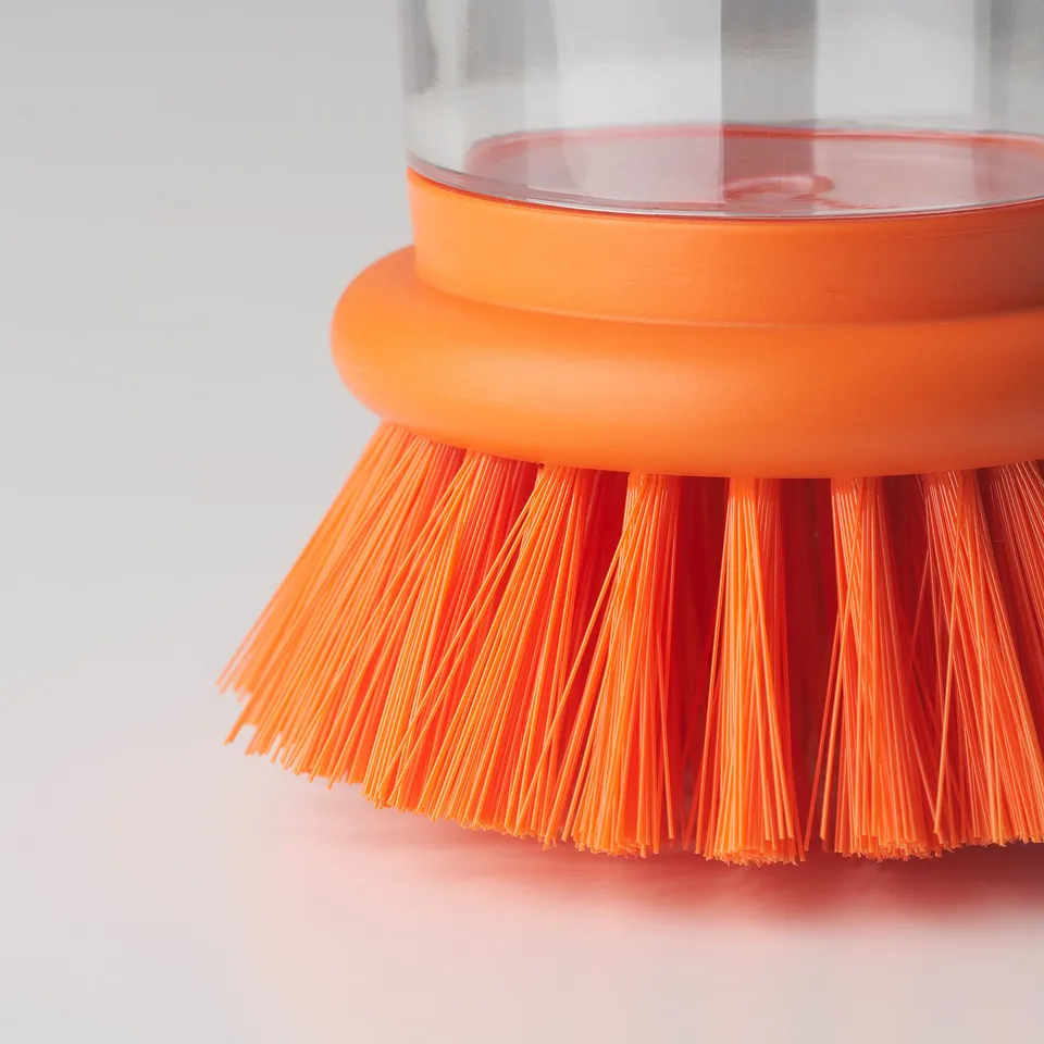 Close-up of bright orange brush with transparent liquid holder, showcasing strong bristles and durable build quality.