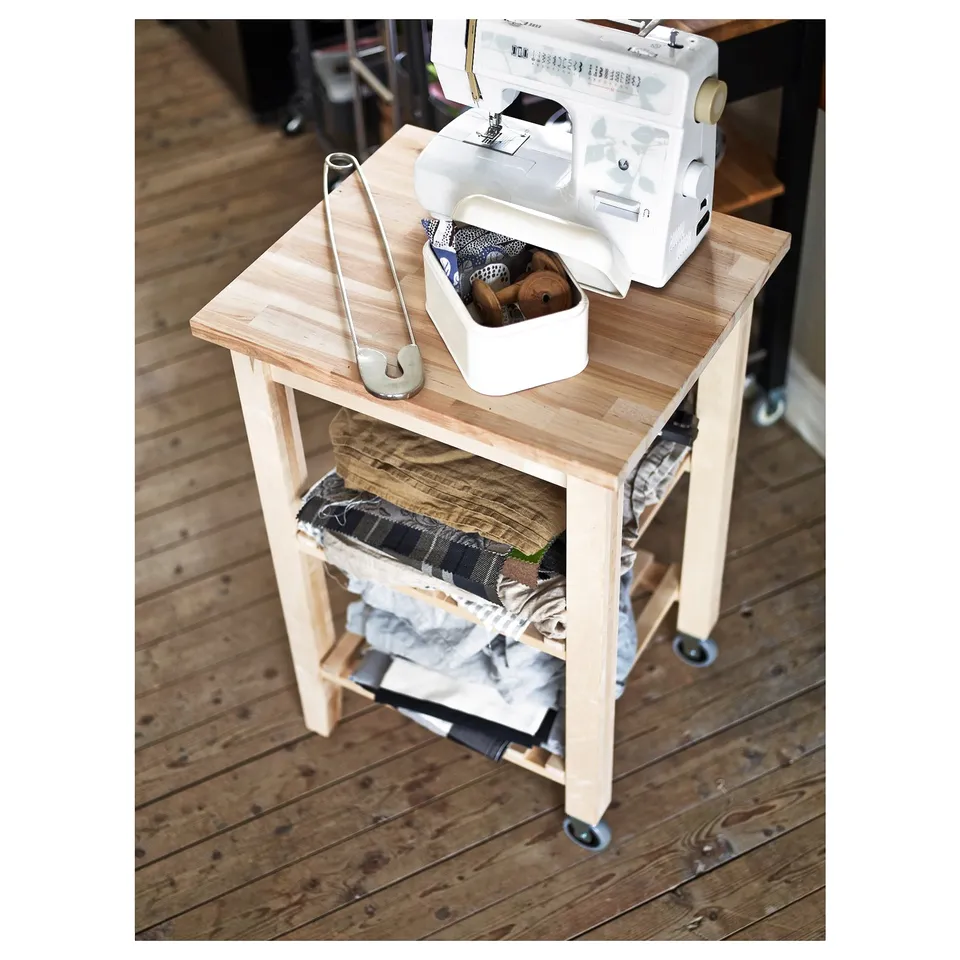 BEKVÄM: light wooden mobile unit with sewing machine, tools, and fabric.