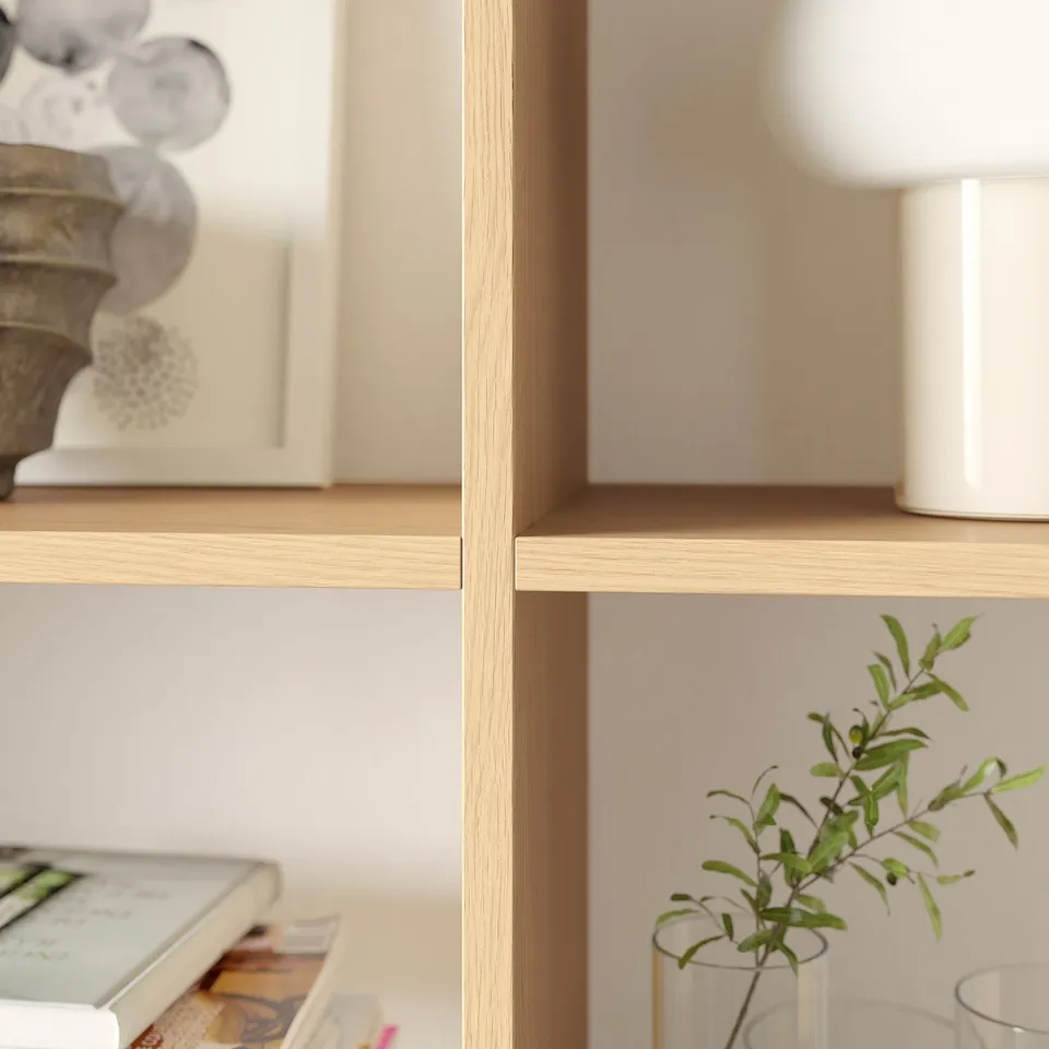 Wooden shelf displays books, vases, and a plant, showing a well-organized living space.