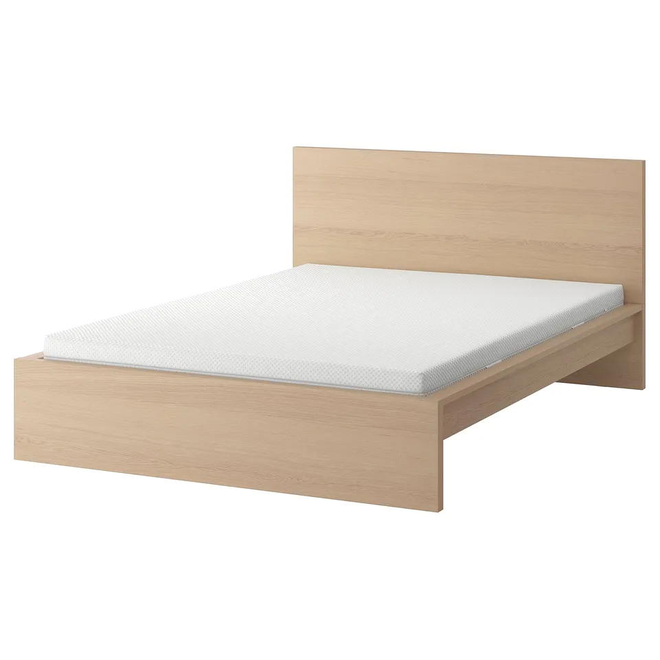 A light wooden MALM bed with a light grey mattress. The design is minimalist with a high headboard.