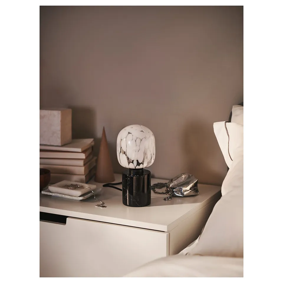 Bedside table with lamp, books, decor.