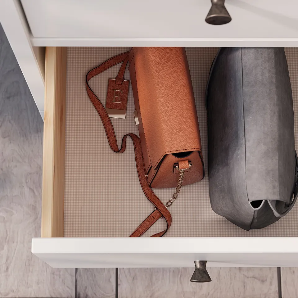 White chest of drawers with tan bag, black bag, wooden drawer edges, and grey interior.