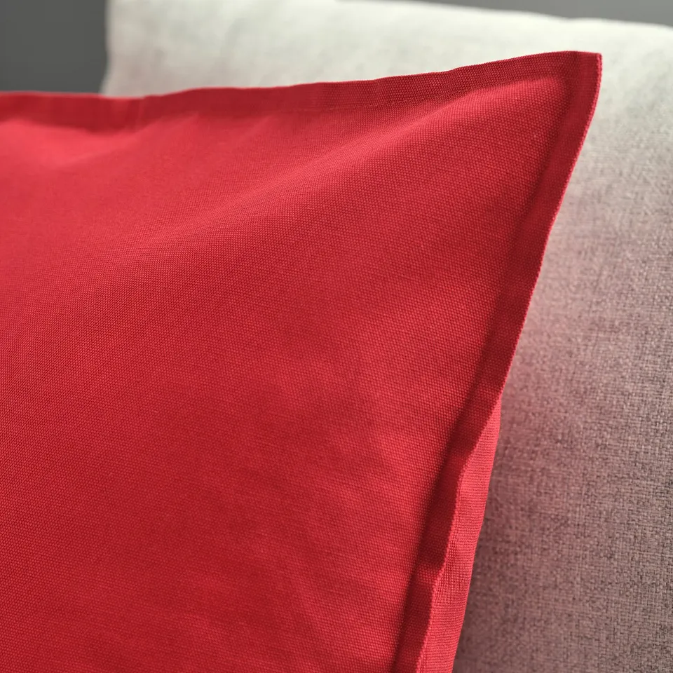 Close-up of vibrant red cushion cover, soft texture visible, smooth finish, neat zip detail.
