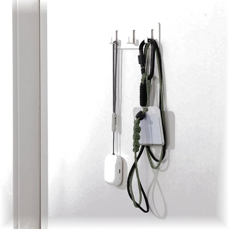 Self-adhesive wall rack with hooks holding items, including a white power bank and a black and yellow chord.