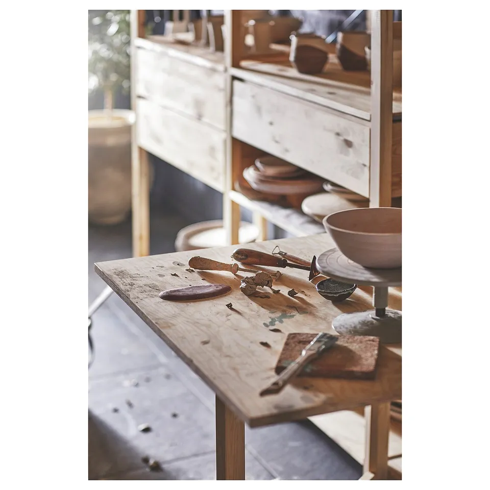 Wooden workbench with tools and pottery, featuring IVAR.