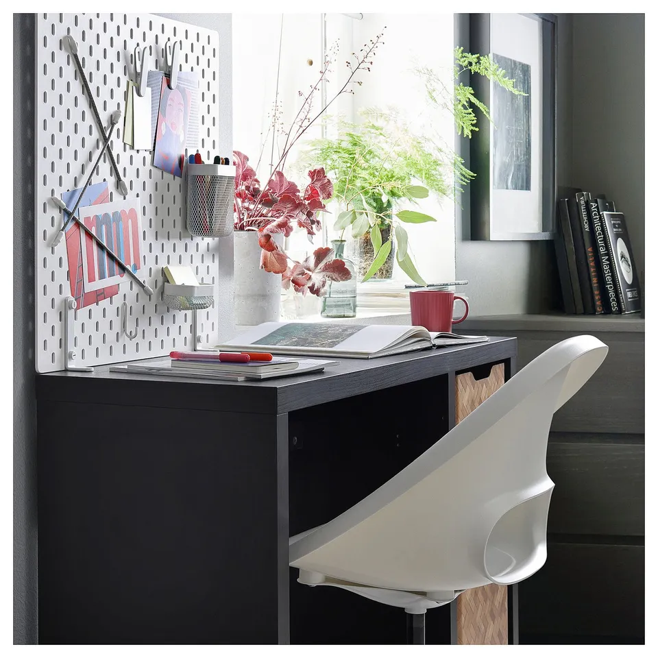 Modern home office setup with black desk, white chair, pegboard, and plants. Minimalist and organised.