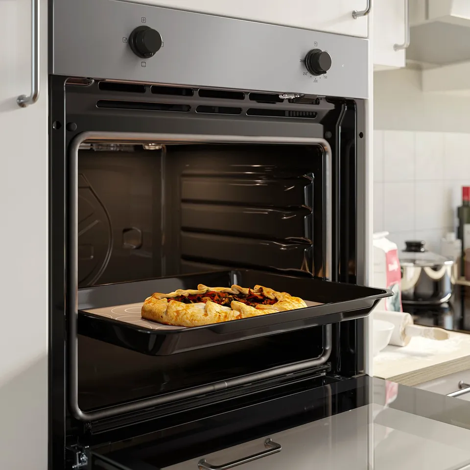 Black oven, open door showing baking tray inside with uneaten food.