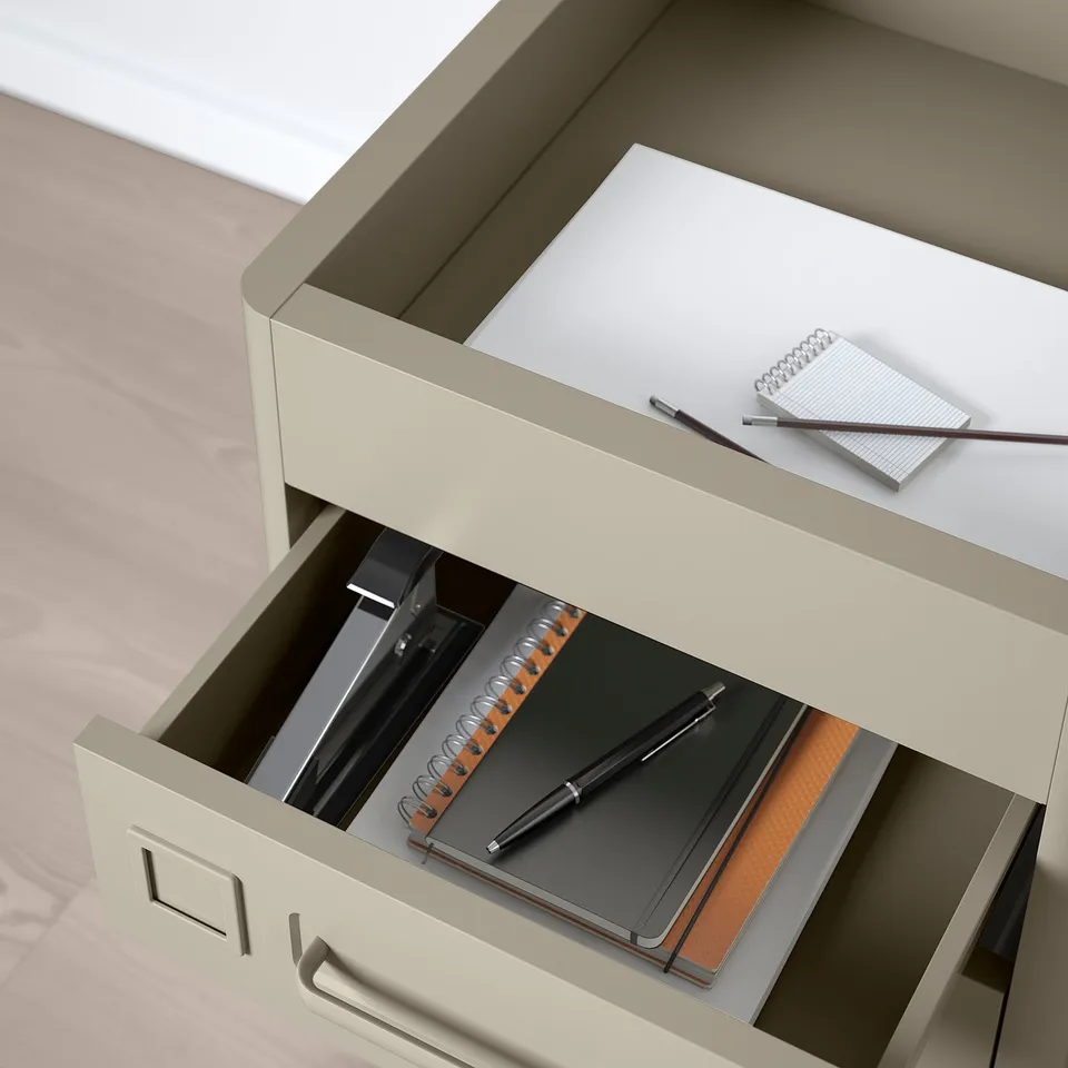 Beige desk drawer open with notebook, pen, showing soft-close feature.