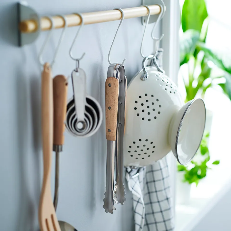 Kitchen hooks with utensils: tweezers, rolling pin, measuring cups, colander. Light wood handles for grip.