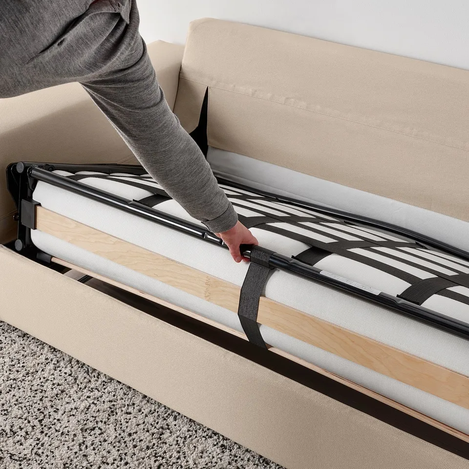 Person converts sofa-bed, pulling out bed frame; VIMLE series sofa-bed transforms easily.