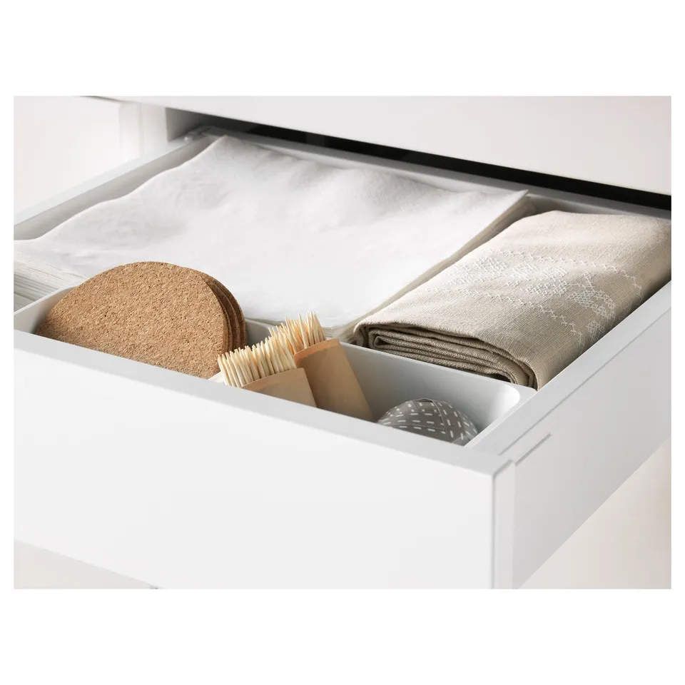 Open kitchen drawer with organised cleaning tools: brush, strainer, towels.