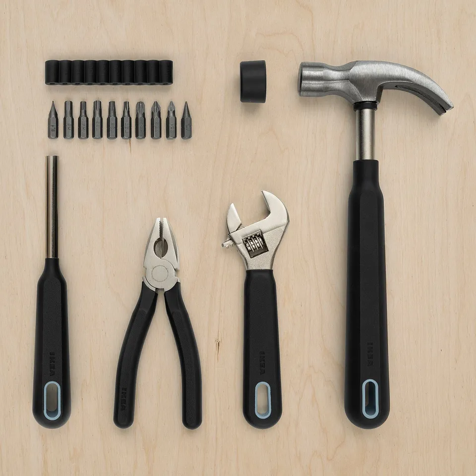 Several black diy tools laid on wood: screwdriver, pliers, wrench, hammer. Essentials for minor repairs.
