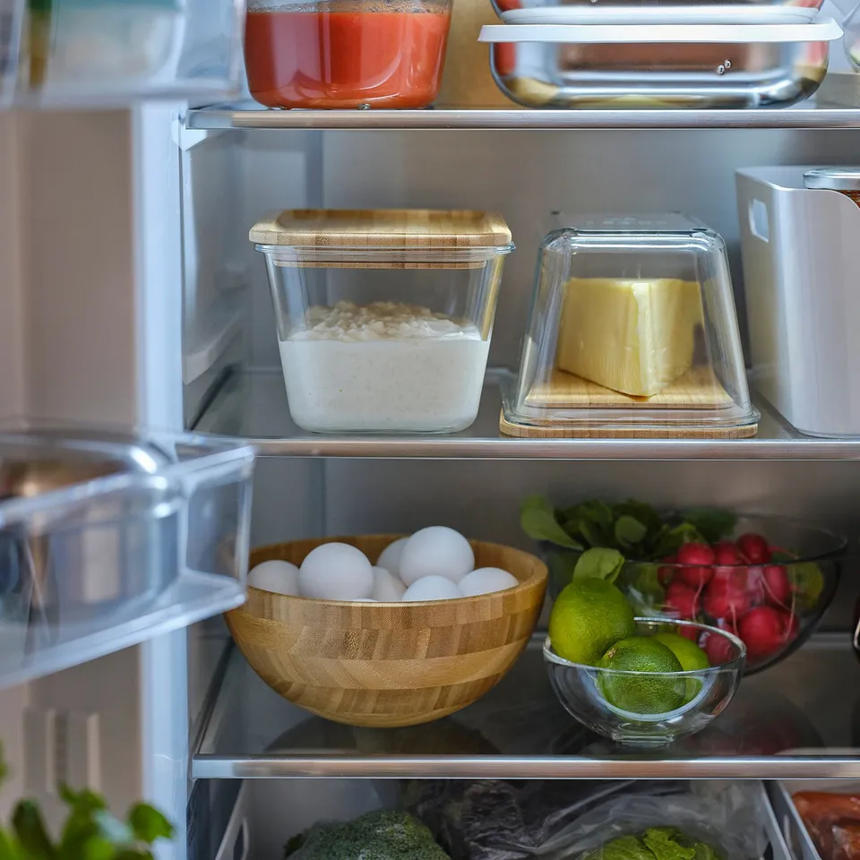 Open refrigerator showcasing IKEA 365+ glass food containers with tight lids storing rice, butter, and fruits.