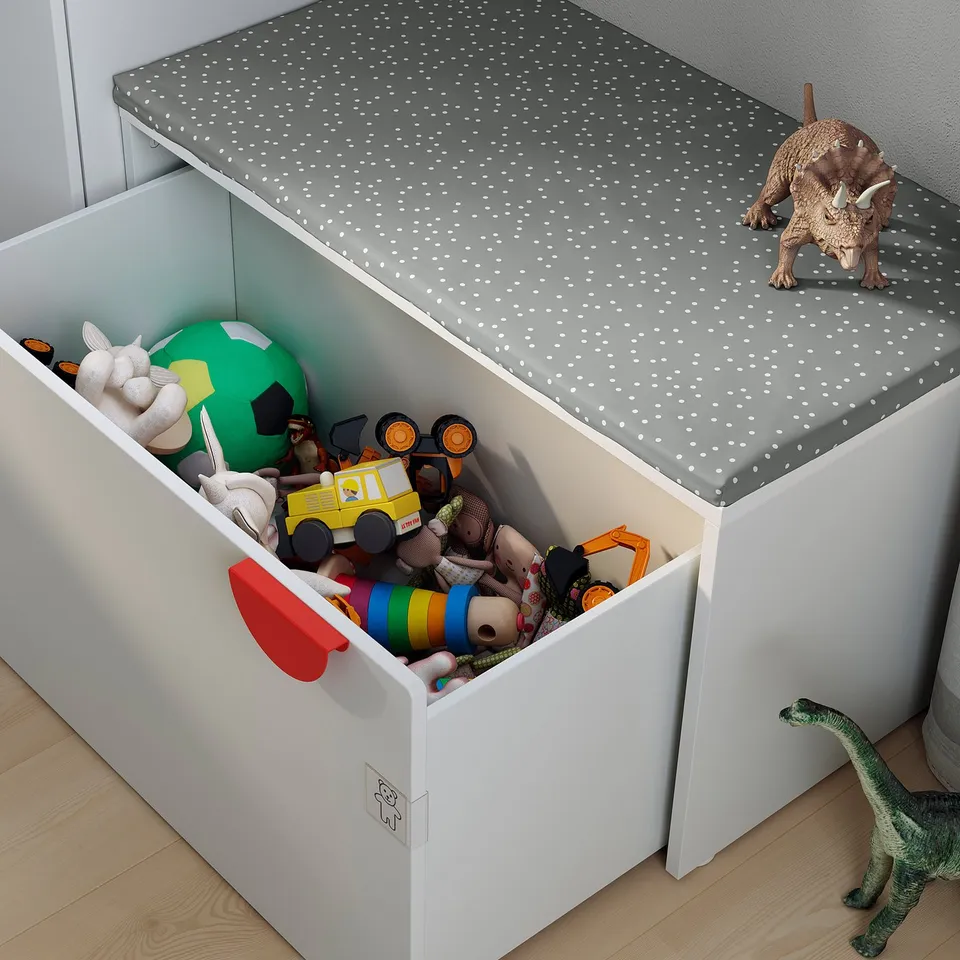 Childs toy box with toys and dinosaurs. White, square, open top.