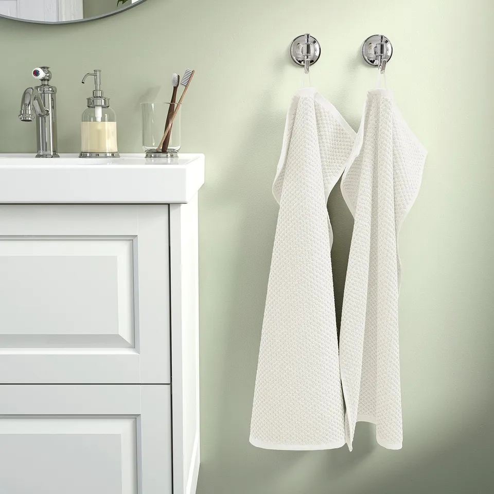 Beige GULVIAL towel on chrome hooks beside white sink cabinet.