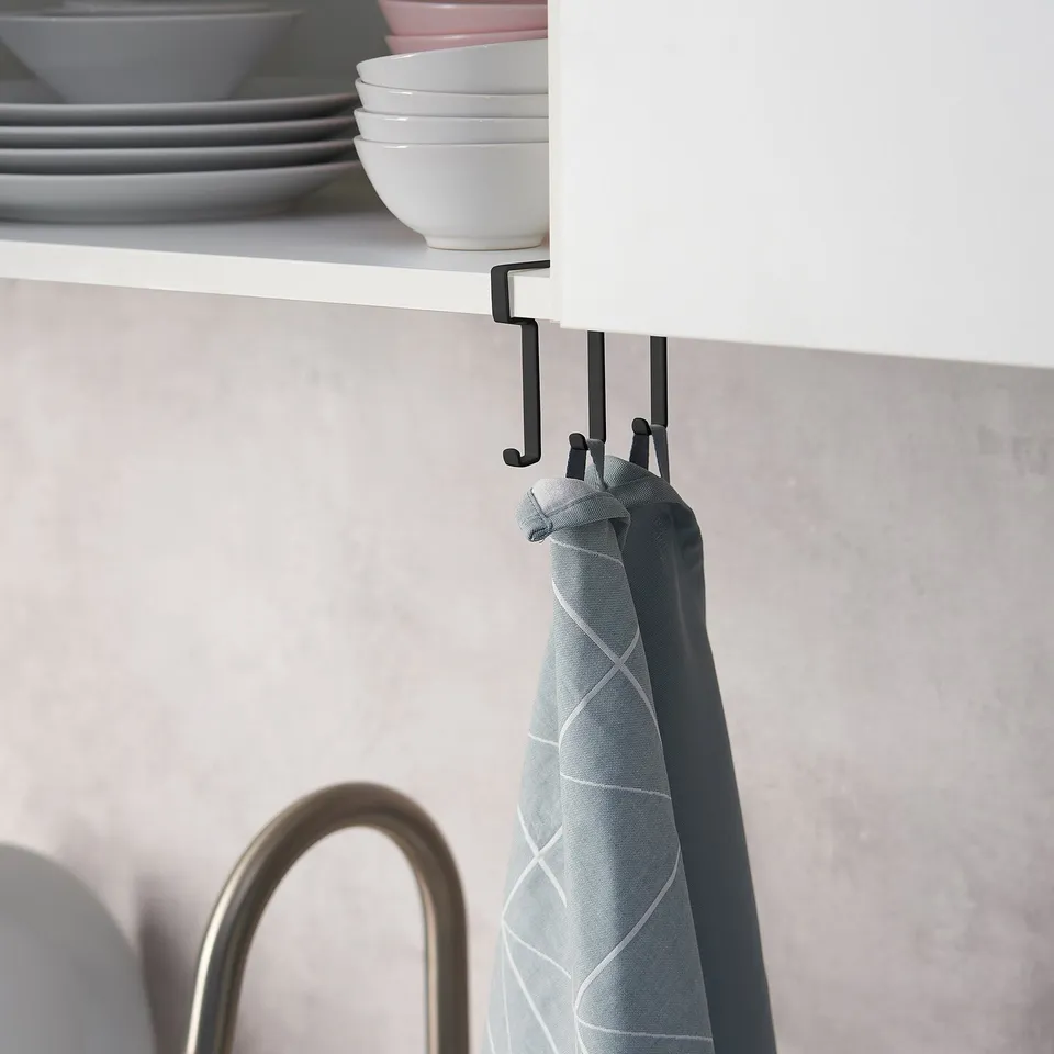 A hook rack attached under a white cabinet holds a light blue tea towel. It efficiently uses space for storage.