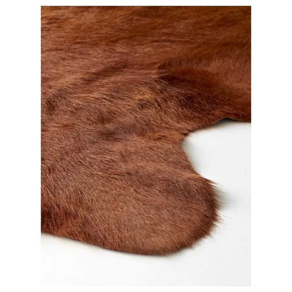 Fur rug on white surface, soft, brown, natural texture.