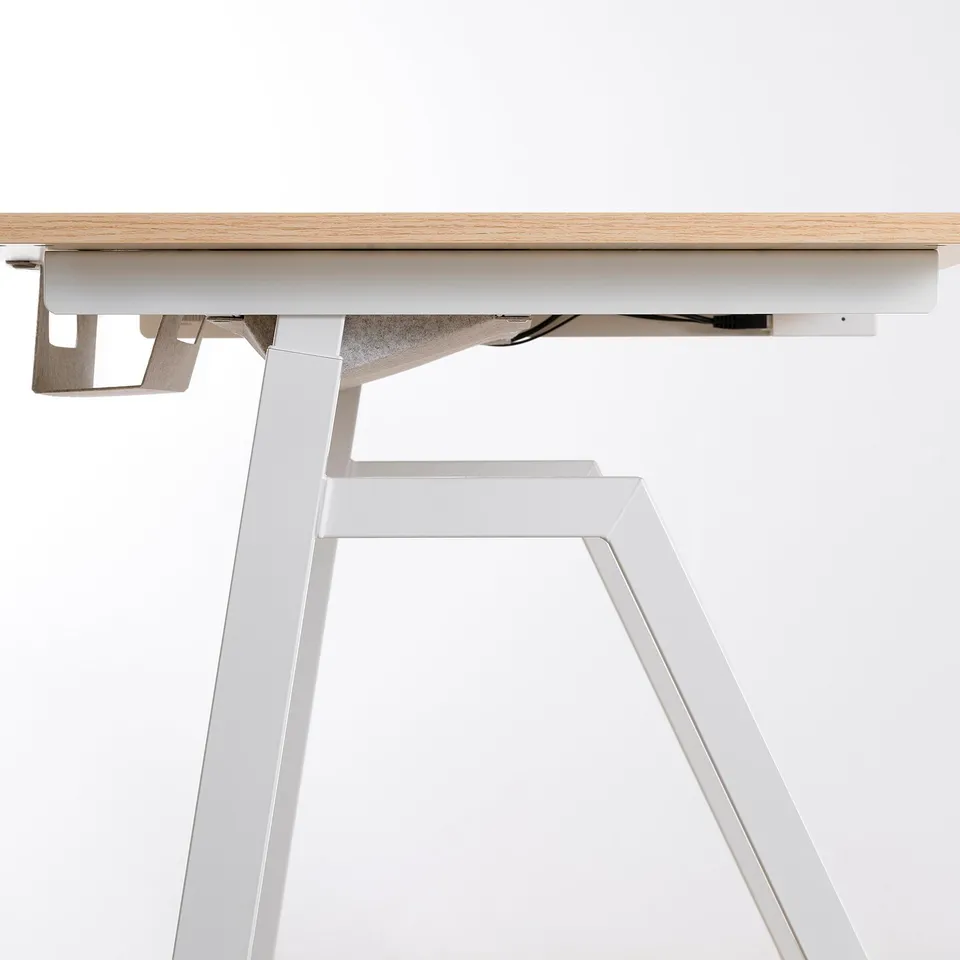Minimalist sit/stand desk in ash wood and white metal, designed for ergonomic use.