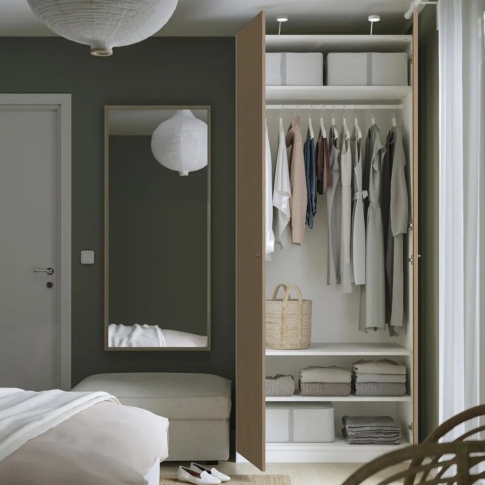 Bedroom featuring a modern PAX wardrobe with open doors, showing hangers and folded clothes inside.