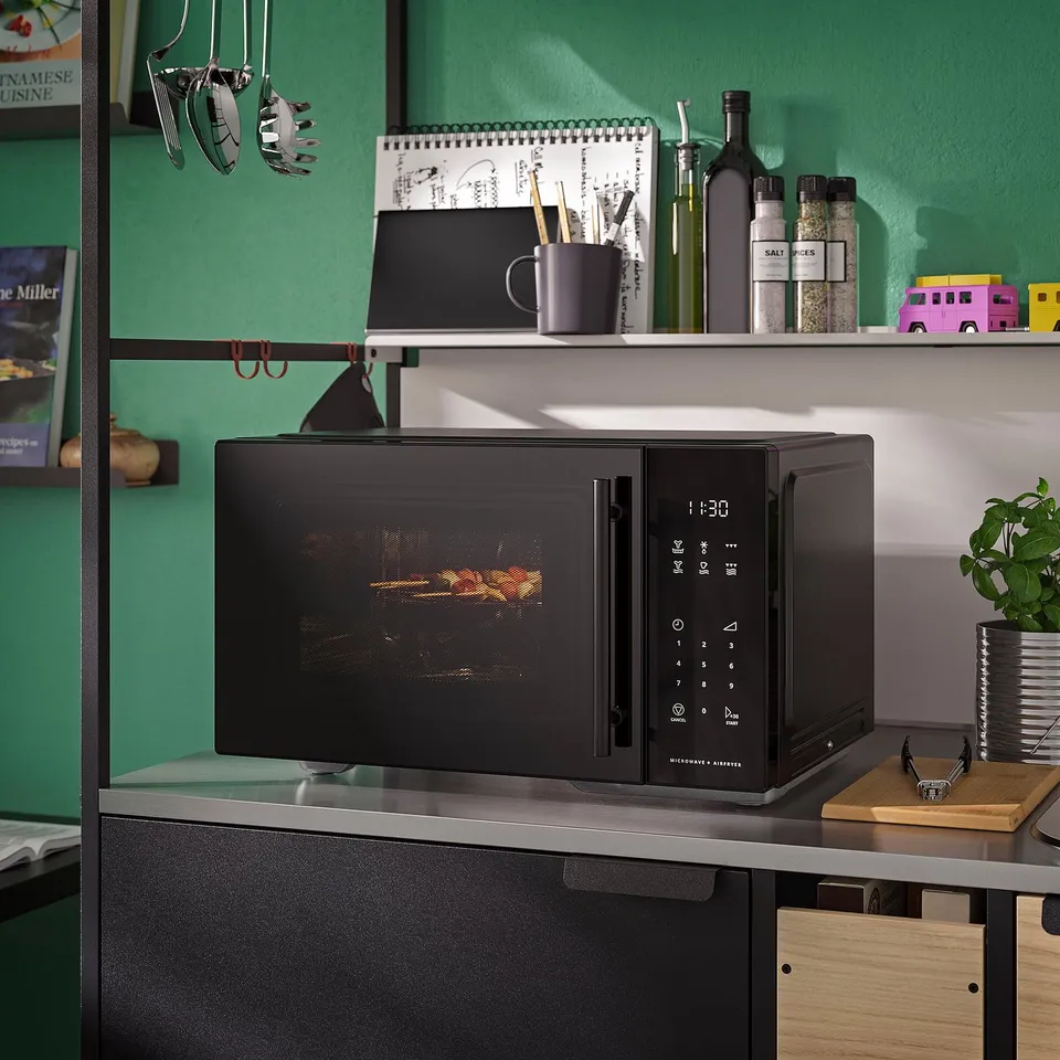 Black GÅTEBO microwave oven on counter, smaller than shelf items, with digital display and air fry tray.