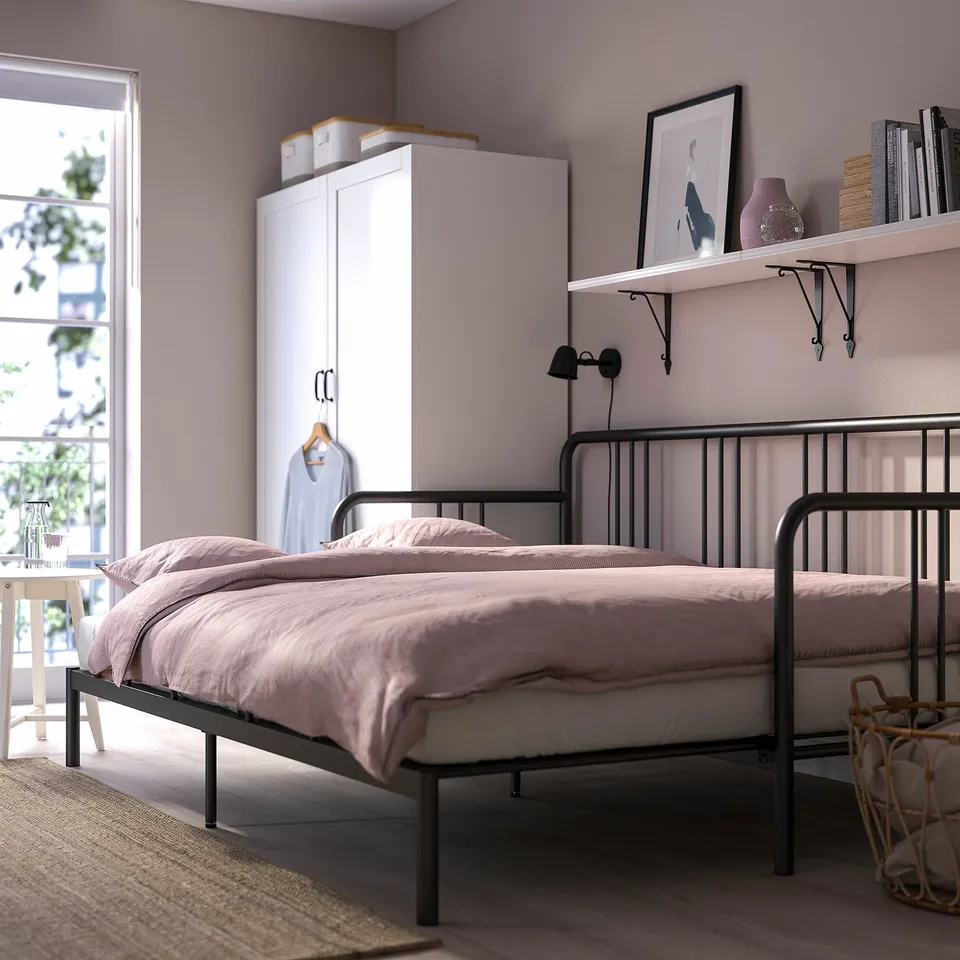 Bedroom with FYRESDAL day-bed, used as a single bed with pink bedding and pillows. White wardrobe and shelves with decorations.