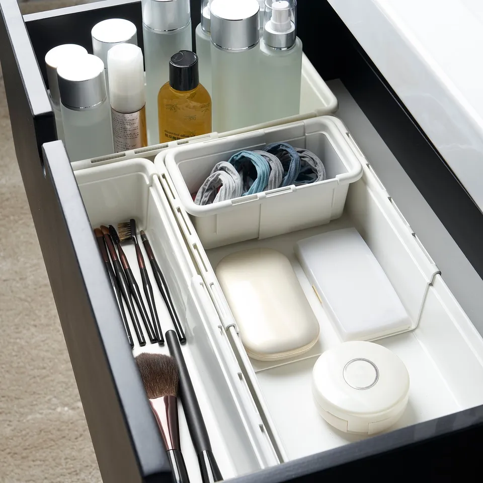 Organised drawer with makeup brushes, hair ties, and skincare bottles neatly stored in dividers.