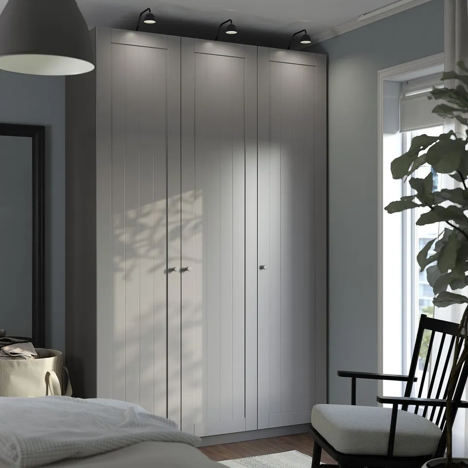 Modern bedroom with grey PAX wardrobe, bed, chair, plant, and lamp.