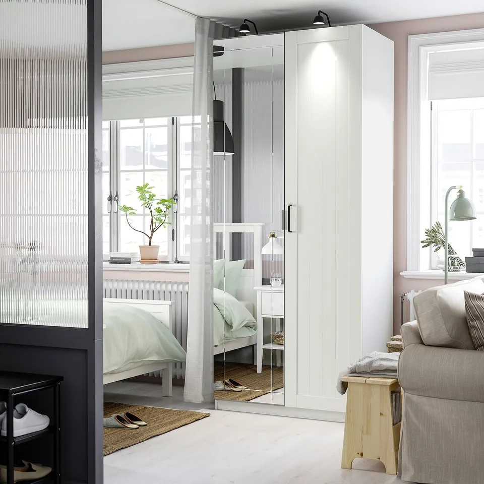 Minimalist bedroom with large lit mirror wardrobe between windows.