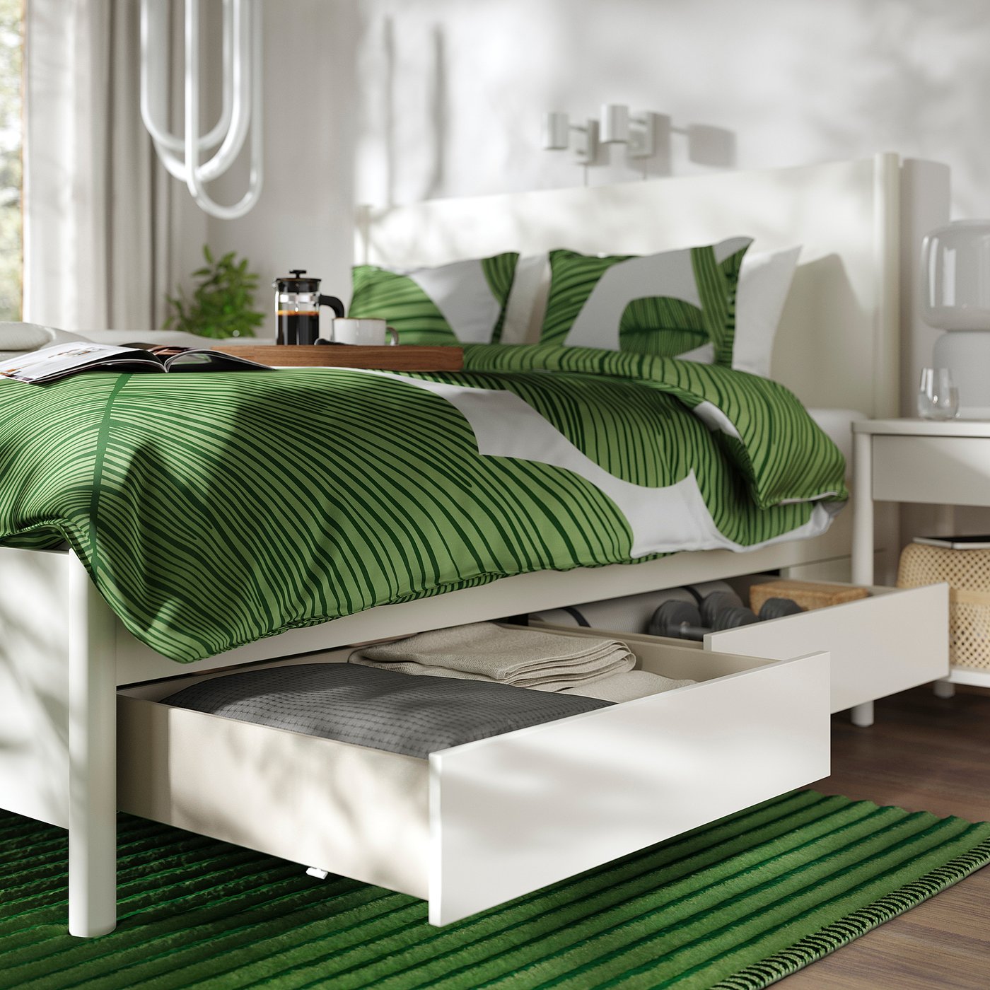 Bed with soft-close drawers open, displaying neatly folded clothes. Green striped bedding and large pillows on the bed.