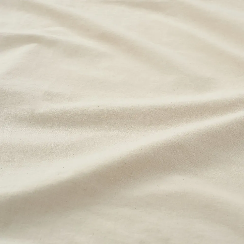 A close-up shot of a soft, textured fabric, likely cotton, displaying its smooth, natural weave and subtle, earthy tone.