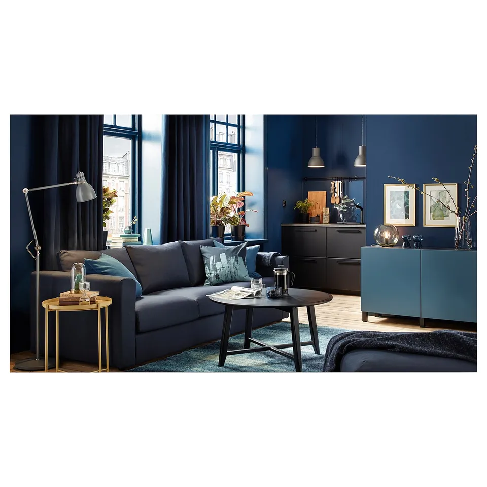 Modern living room with blue sofa, coffee table, hanging lights, small tables, dark blue walls, and city view.