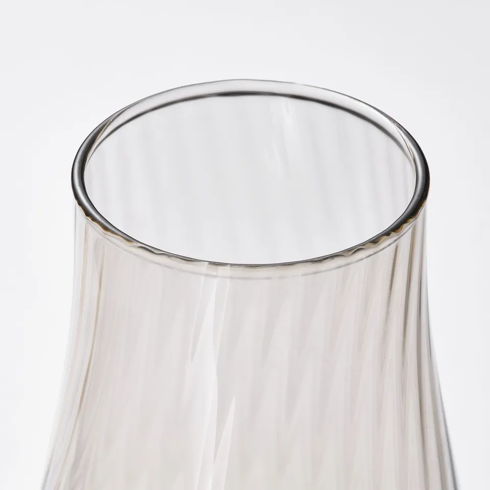 Elegant, clear glass vase with rippled texture, catching soft light.