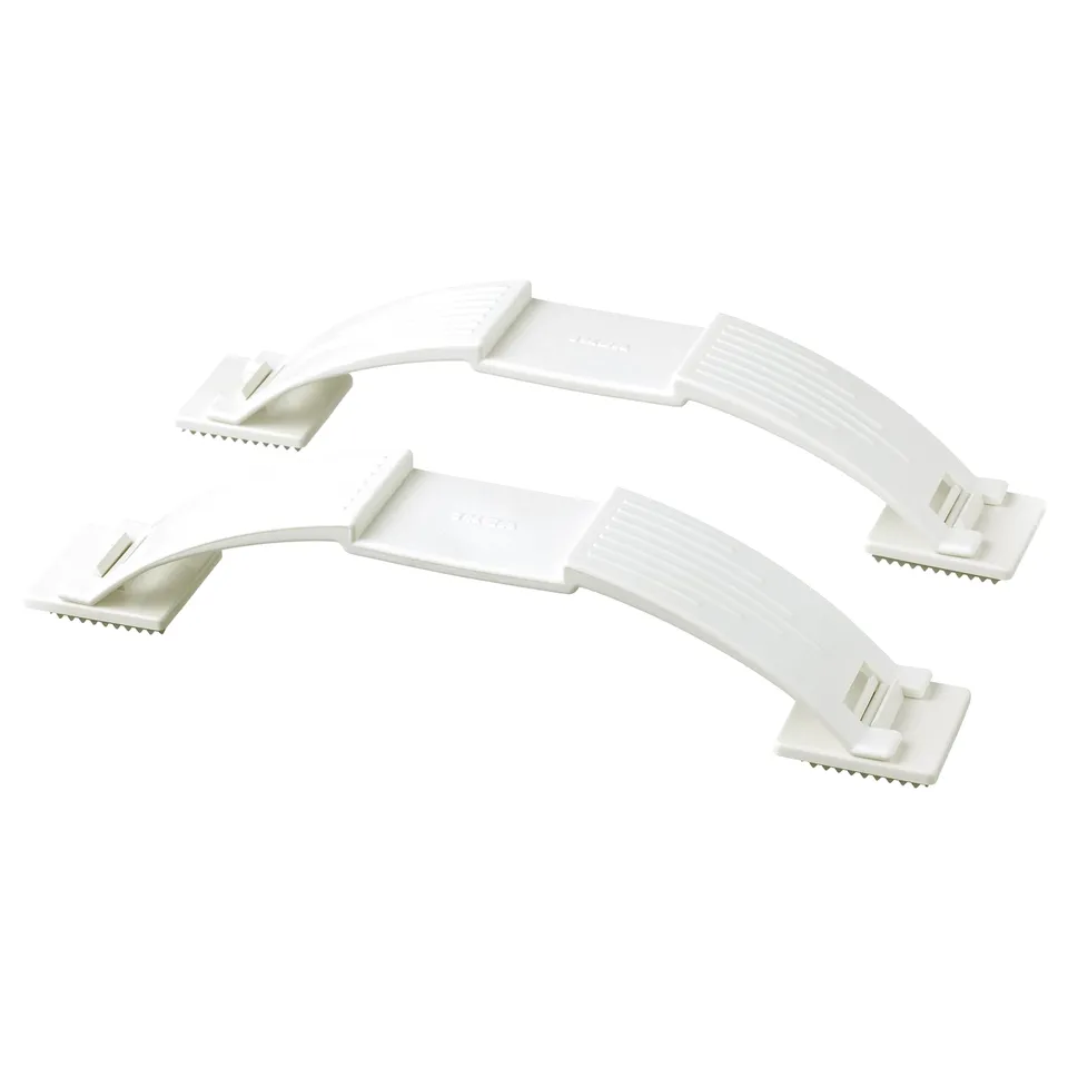 Two white plastic PATRULL door stoppers. They each have a rectangular base, curved arm, and small teeth to grip the door.