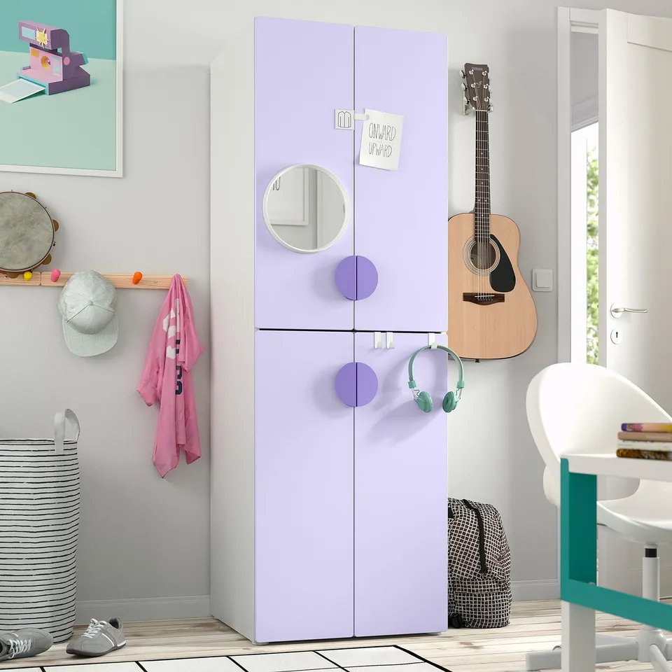 A kids bedroom featuring a tall lavender SMÅSTAD wardrobe with mirrored doors. It stands between a guitar and a desk, larger than nearby items.