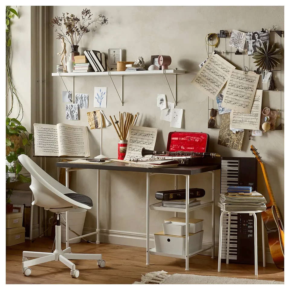 Creative workspace with black desk, white chair, musical notes, books, and guitar.