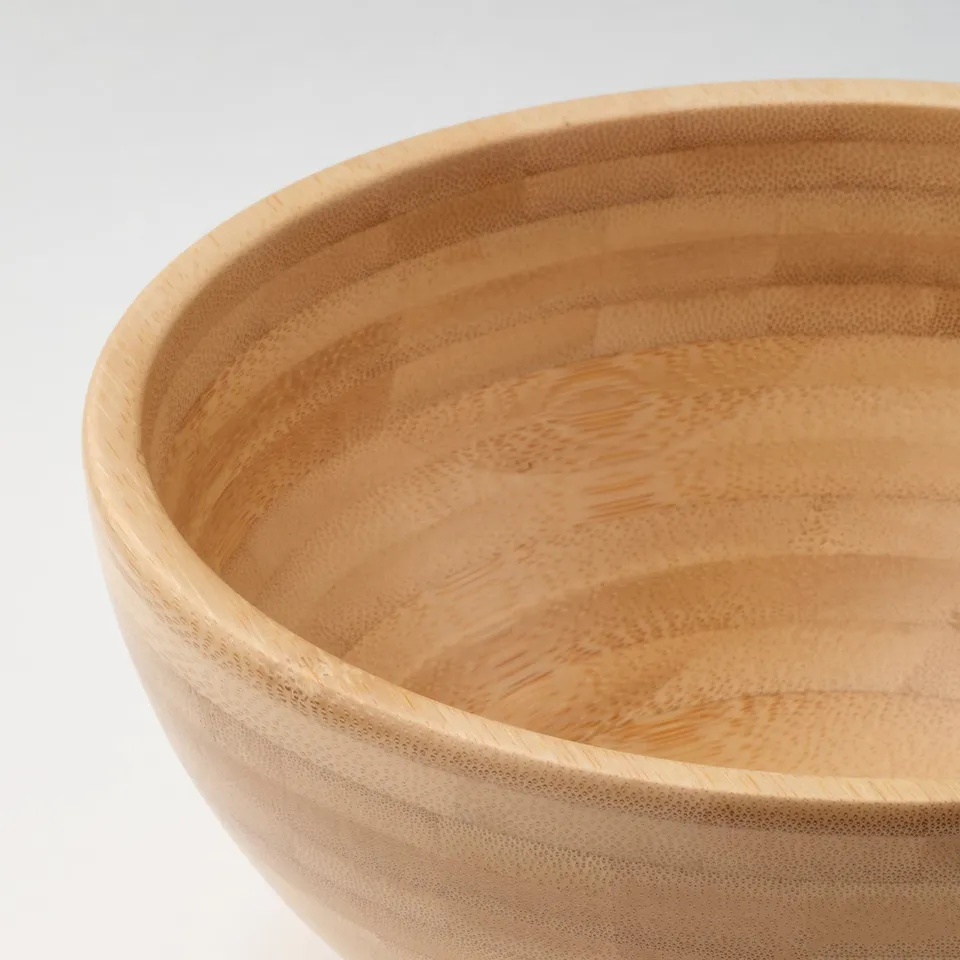 Wooden bowl with smooth finish, round shape, and visible wood grain texture, resting on a white surface.