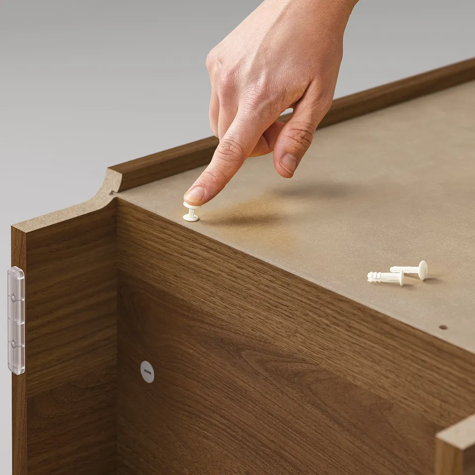 A person assembles a BILLY bookcase with wooden texture and white plastic hinges.
