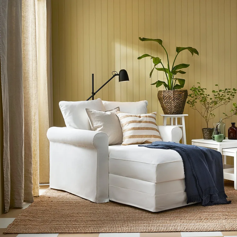 A cosy living room with LOHALS white chair, jute rug, beige wall, and natural decor.