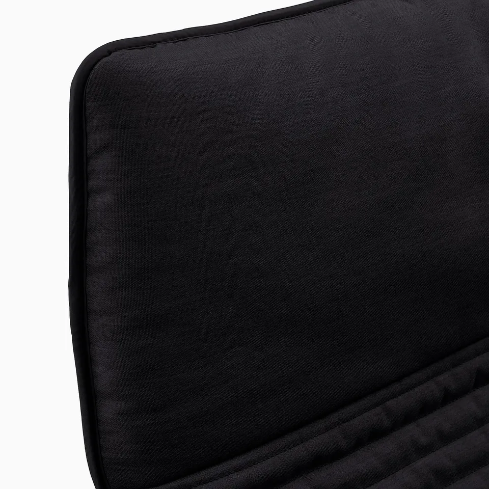 Black cushioned chair seat with neat sewing and smooth fabric, showcasing high-quality upholstery.