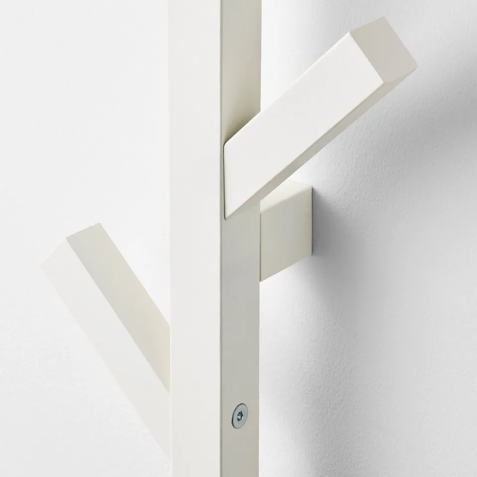 Modern, minimalist wooden coatrack with three hooks, mounted on white wall.