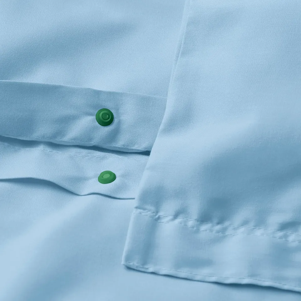 Close-up of duvet with green press-stud closure, showcasing lightweight, smooth fabric with fine sheen.