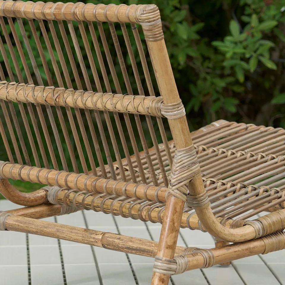 Wicker outdoor furniture on a tiled surface. Close-up shows intricate weaving and natural material texture.