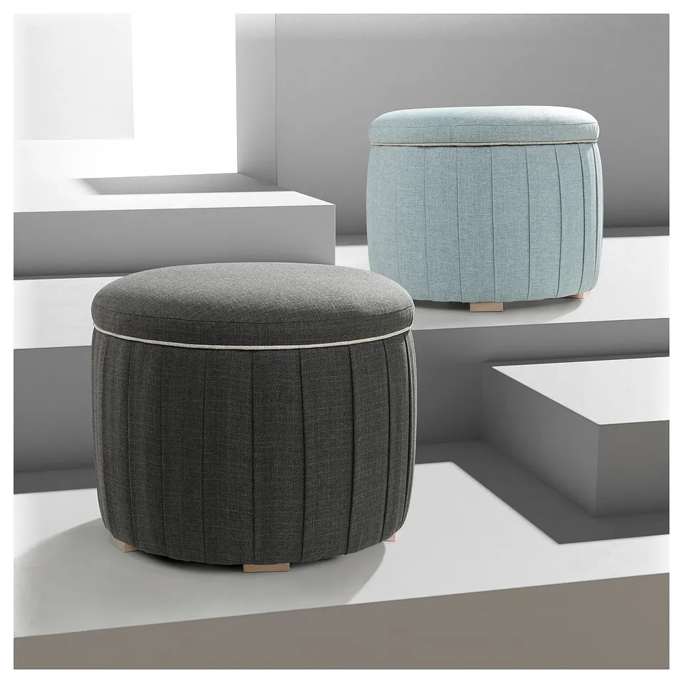 Two modern round storage ottomans, one dark grey, one light blue, with pleated design and wooden legs.