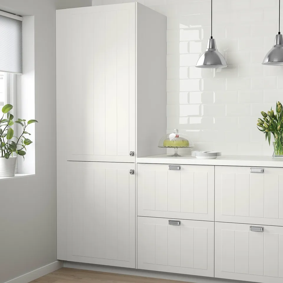 Kitchen with white STENSUND cabinets, wooden floor, potted plants, and hanging lamps.