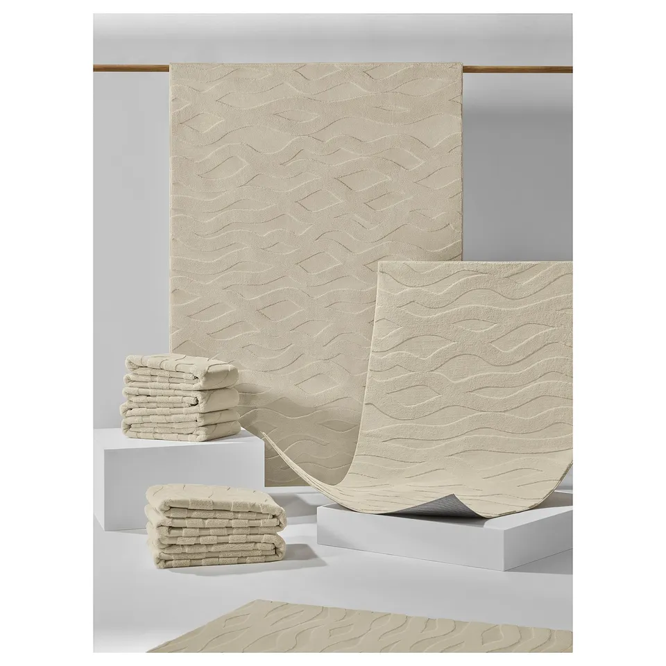 VÄXELFEL rugs in beige. They feature a plush, textured wavy pattern and a non-slip back.