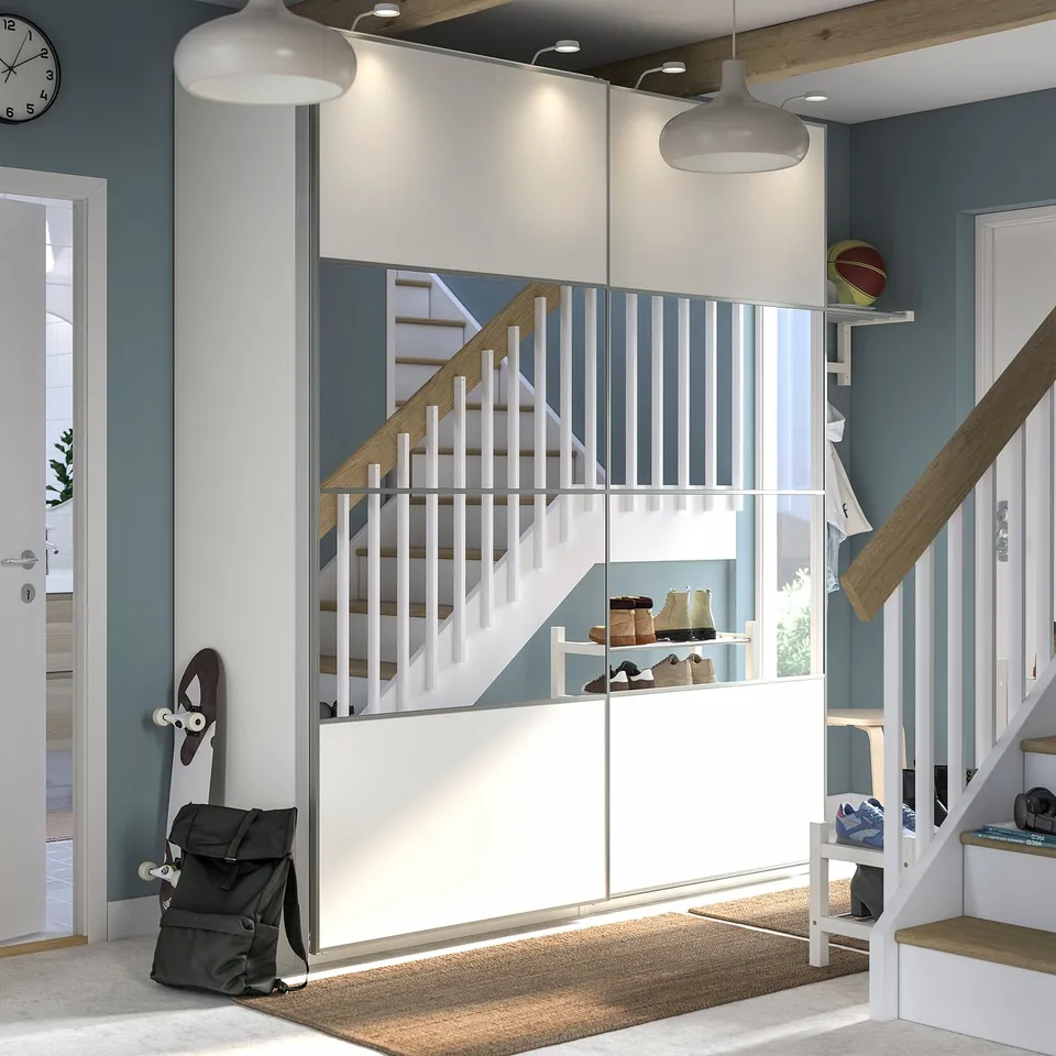 Modern entryway with white PAX storage, mirrored doors, stairs, grey walls, and wooden accents.