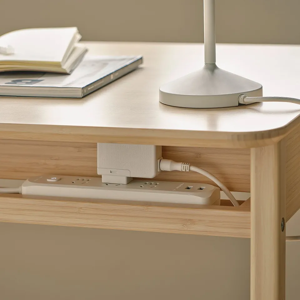 A modern desk made of bamboo has built-in power strips and usb ports for convenient device charging.