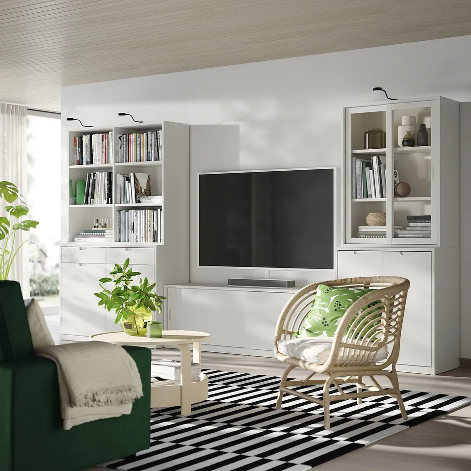Living room with off-white TONSTAD furniture, tv, wicker chair, striped rug, plants.