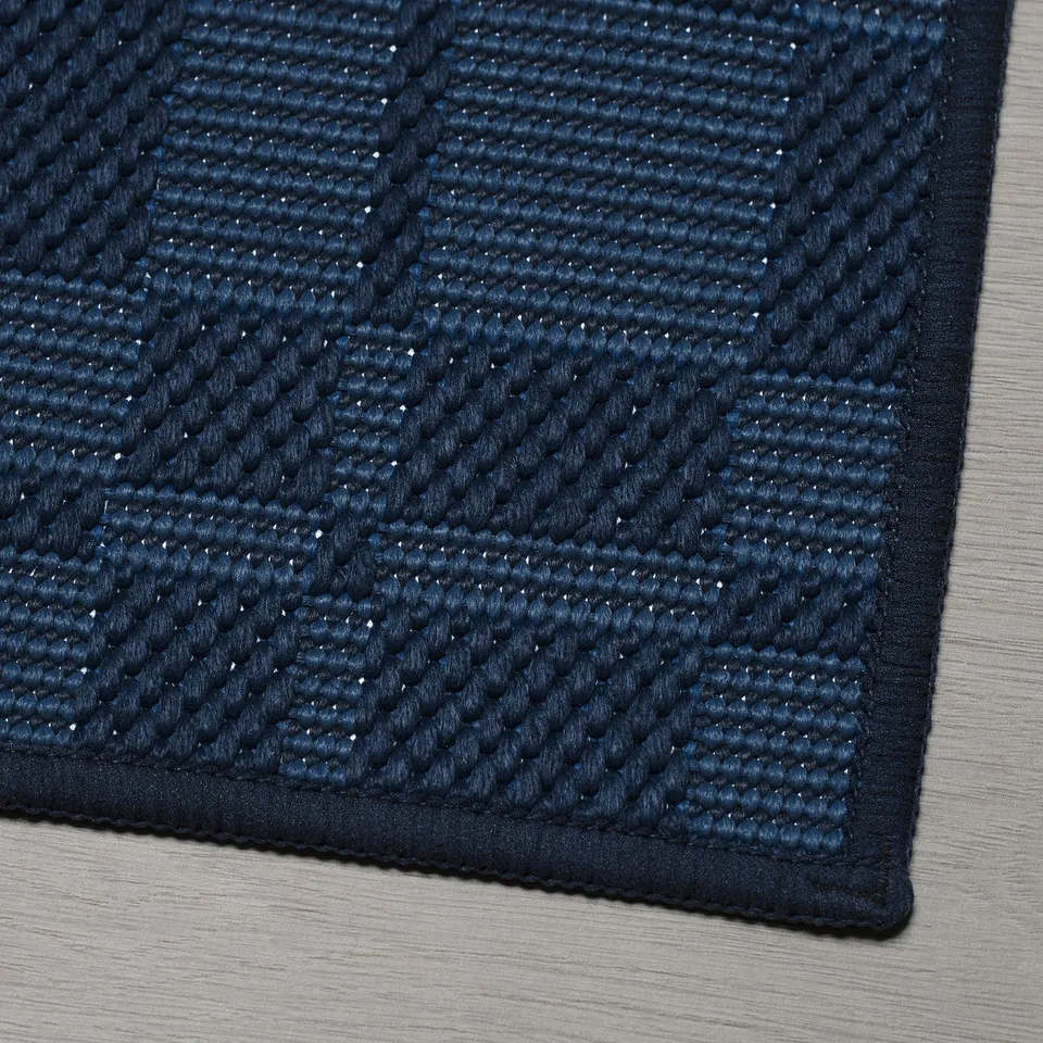 Close-up of a textured, blue, eco-friendly rug on a wooden surface.
