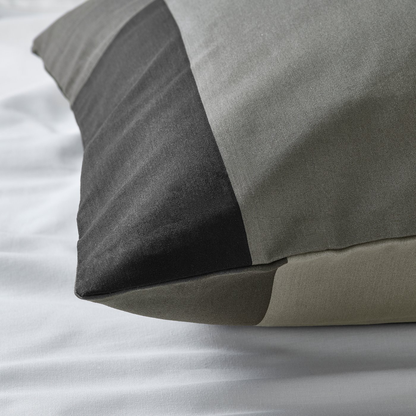 Close-up of plush, woven pillowcase in dark grey, showcasing its soft, textured fabric and neat stitching.